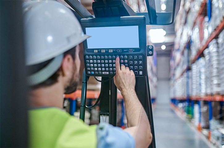 A warehouse worker enters information using an HMI panel.