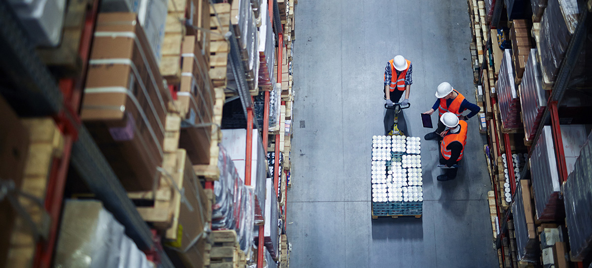 Three warehouse employees check the batch data with the actual quantity of goods using a tablet app.
