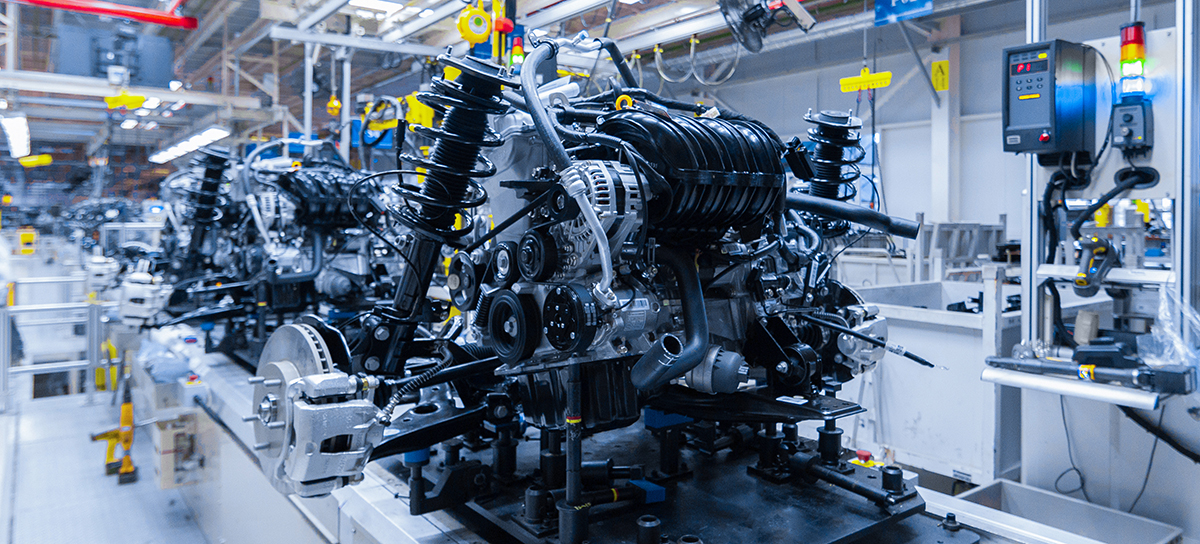 A conveyer band with an automobile engine at a plant.