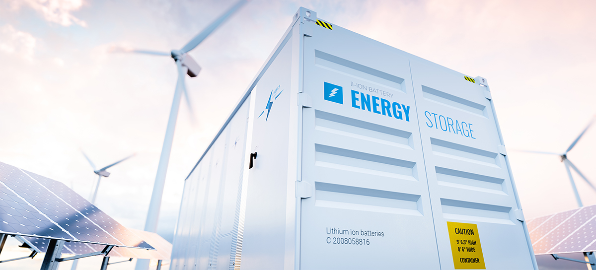 An industrial battery energy storage system, solar panels, and wind turbines.