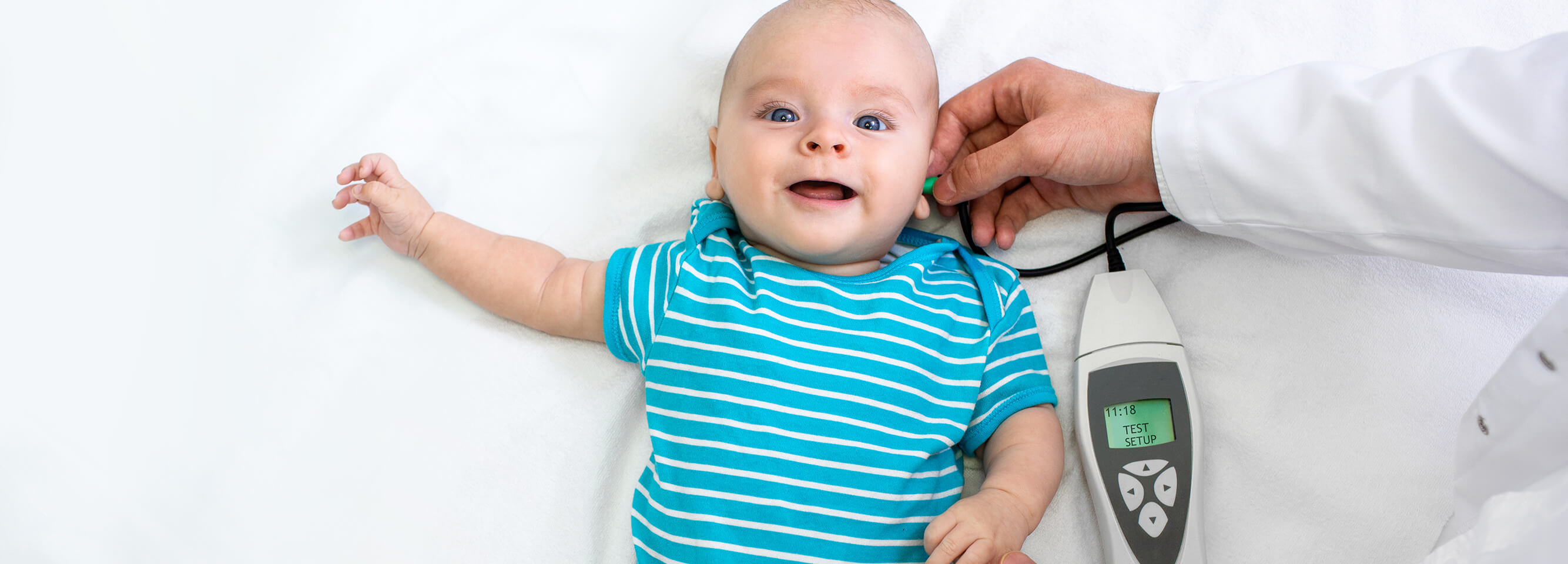 A doctor is conducting a hearing test for an infant using a portable electronic device.