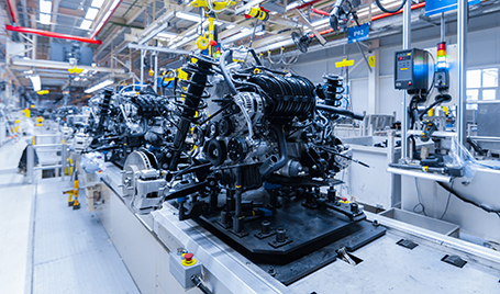 A conveyer band with an automobile engine at a plant.