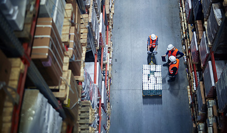Three warehouse employees check the batch data with the actual quantity of goods using a tablet app.