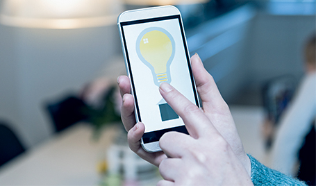 A man turns on the light using a mobile app.