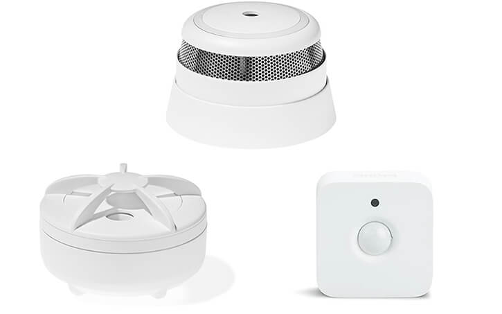 A collage of smart home sensors: a motion sensor from Philips, a smoke alarm, and a water leak detector from Develco.