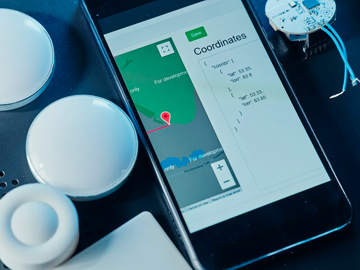 GPS tracking devices and a smartphone with an app on the screen.