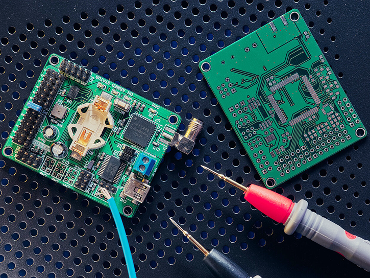 Two green printed circuit boards and tools lying on a desk.