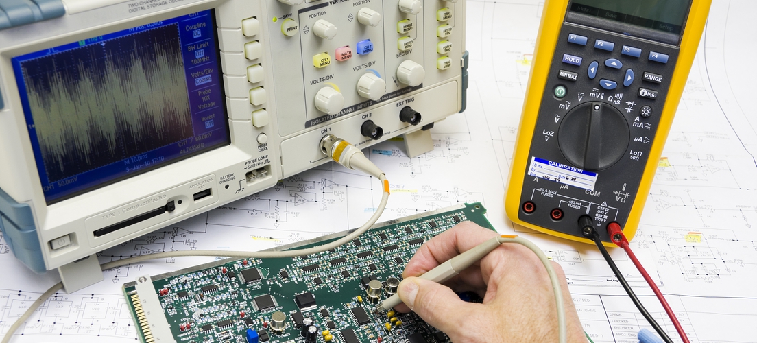 An electronics engineer is testing a printed circuit board with tools.