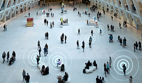 A shopping mall with many visitors using mobile devices.