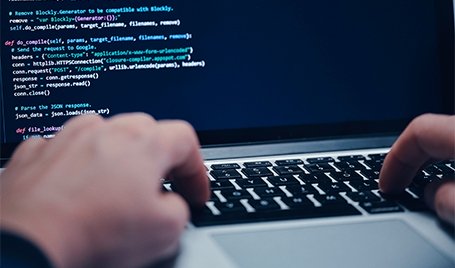 A person is typing a programming code on a laptop computer.