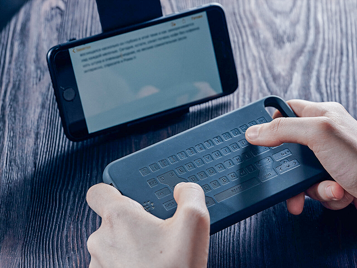 A man types the text not on a smartphone, but on a special touch case for it. The text is displayed on the smartphone screen.