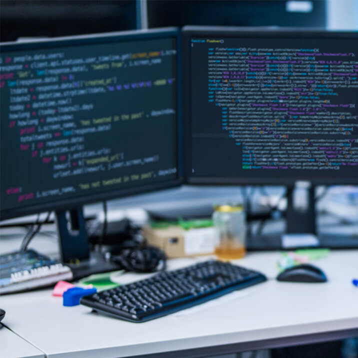 Two computer monitors with pieces of code on the screens.