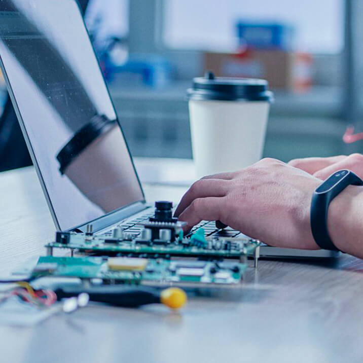 An Integra Sources engineer uses a laptop to write middleware for a custom electronic device.