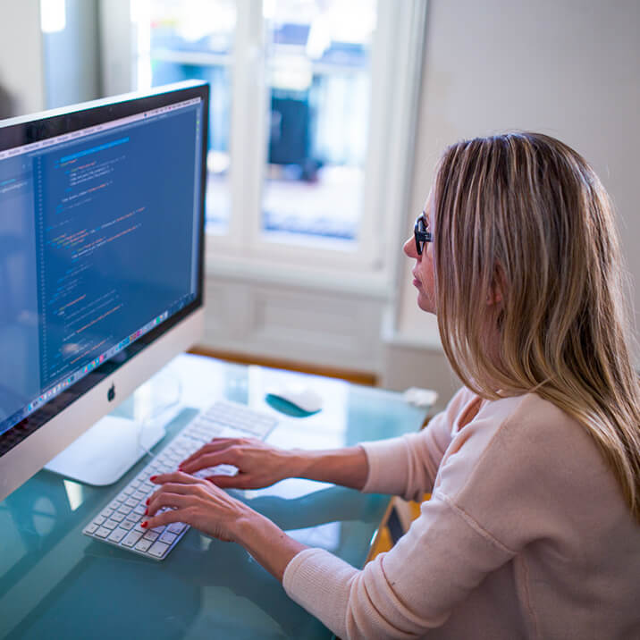 A female programmer is working on a PC to create a root file system.