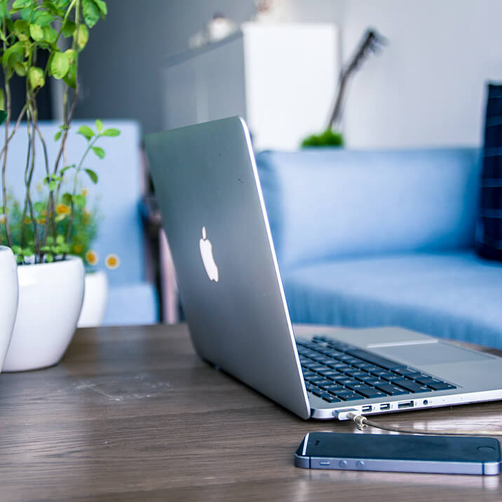 A MacBook on a coffee table with potted plants.