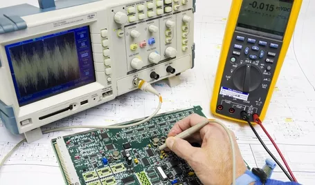 An electronics engineer is testing a printed circuit board with tools.