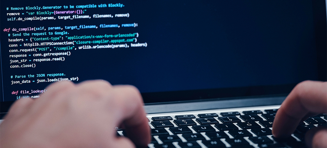 A person is typing a programming code on a laptop computer.