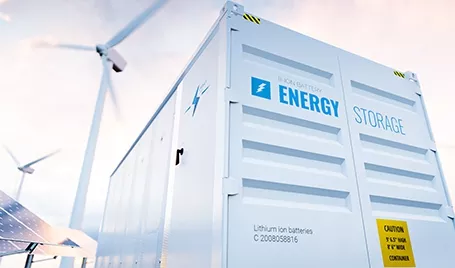 An industrial battery energy storage system, solar panels, and wind turbines.