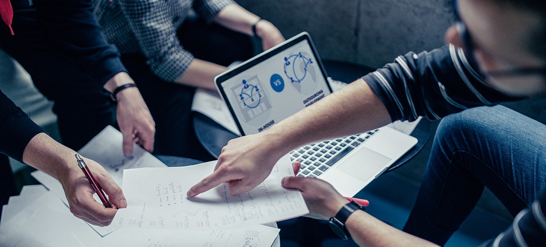 Three persons working with papers and a laptop.